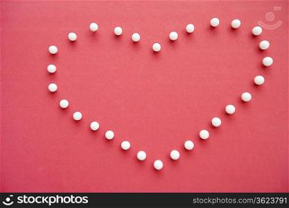 Close-up of push pins forming heart shaped over pink foreground