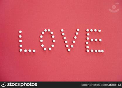 Close-up of push pins spelling love over colored background