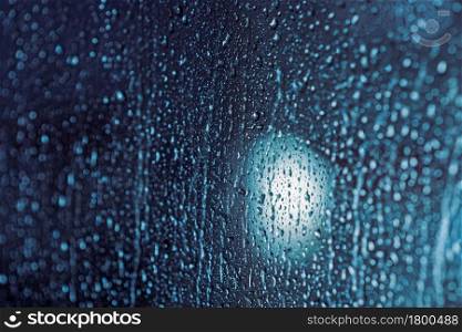 Close up of rain drops on the window in rainy night, cool lights