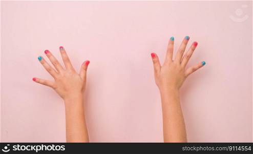 Close-up of raised child hand showing nail polish on pastel pink background in studio. Pack of Gestures movements and body language.