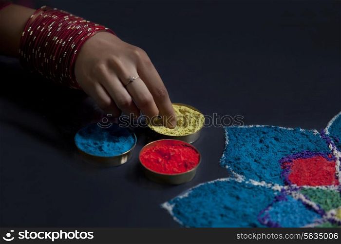 Close-up of rangoli and female&rsquo;s hand