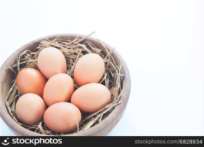 Close-up of raw chicken eggs in wooden bowl isolated on white background