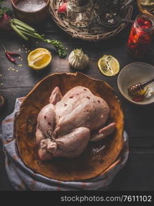 Close up of raw whole chicken on dark rustic background with ingredients for tasty home cooking. Preparation and chicken marinating with lemon, honey and mustard. Home cuisine. Top view