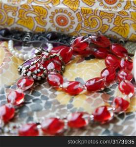 Close up of red bead necklace against pattern mosaic.
