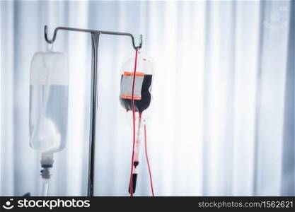 Close-up of Red blood bag and normal saline hanging in hospital ward