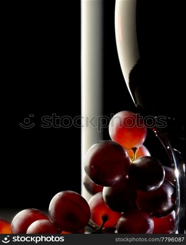 Close-up of red grapes with glass and bottle in background
