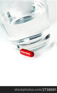 Close up of red pill and water on a high key background