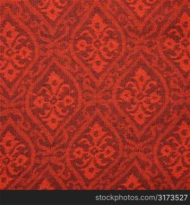 Close-up of red textural vintage fabric with repetitive shapes and designs.