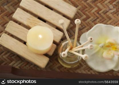 Close-up of reed diffuser with candle and orchid