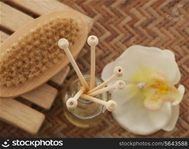 Close-up of reed diffuser with foot brush and orchid