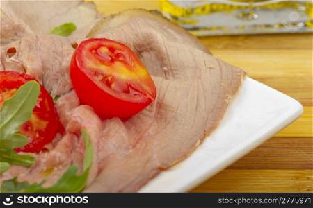 Close up of roast beef with tomato and rocket