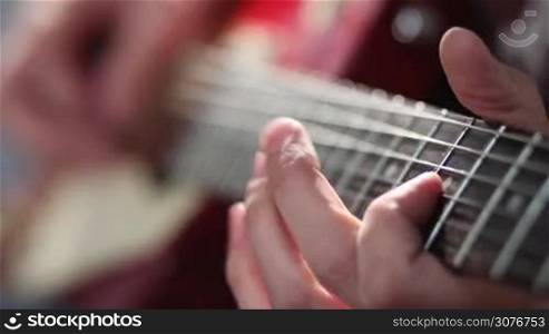 Close up of rock musician hands playing electric guitar using bend technique during rehearsal session in recording studio. Guitarist bending the electric guitar strings with his fingers on frets.