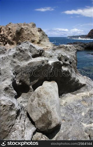 Close-up of rocky shoreline with ocean and blue sky in Maui, Hawaii.