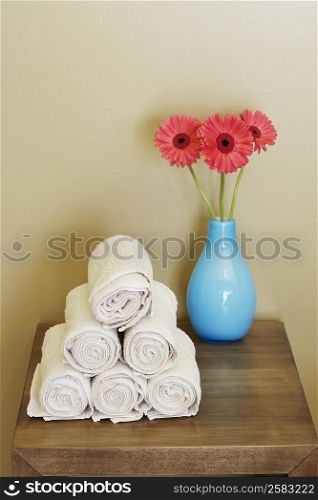 Close-up of rolled up towels with a flower vase