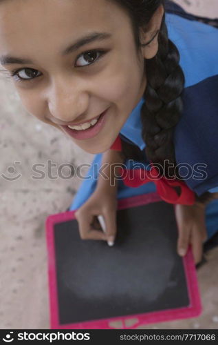 Close up of rural school girl writing on slate 