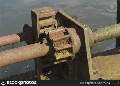 Close up of rusty iron rack and pinion on old weir.