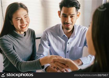 Close-up of salesman shaking hands with lovers who are customers In her office in the house purchase agreement Asian women and men smiling happily