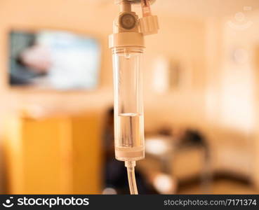 Close-up of Saline solution drip for patient and infusion pump on blurred luxury VIP room background in hospital.