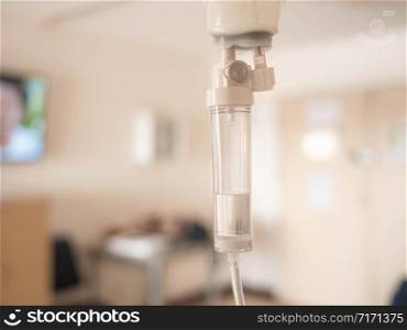 Close-up of Saline solution drip for patient and infusion pump on blurred luxury VIP room background in hospital.