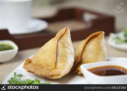 Close-up of samosas with sauce in plate
