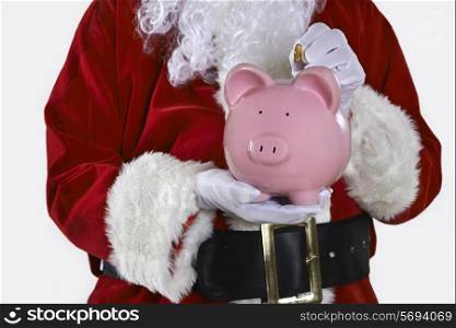 Close Up Of Santa Claus Putting Coin Into Piggy Bank