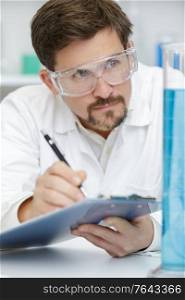 close up of scientist writing test results in lab