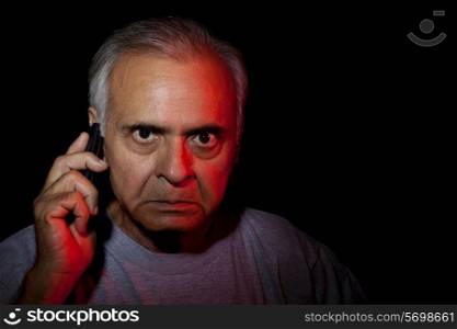 Close-up of senior angry man holding mobile phone