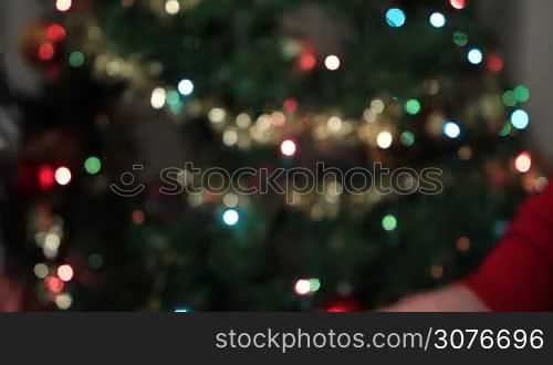 Close up of senior couple in love holding hands expressing love and support over blurred Christmas tree background. Seniors holding hands showing their commitment to each other.