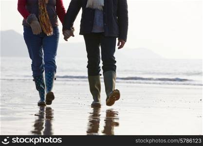Close Up Of Senior Couple Walking Along Winter Beach