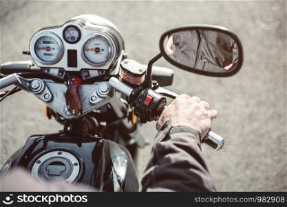 Close up of senior man hand steering motorcycle on the road. Senior man hand steering motorcycle on road
