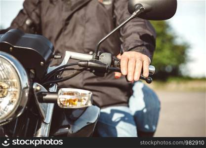 Close up of senior man steering motorcycle on the road. Senior man steering motorcycle on road