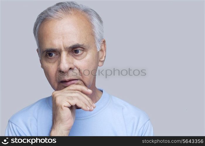 Close-up of senior man thinking over colored background