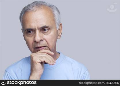 Close-up of senior man thinking over colored background