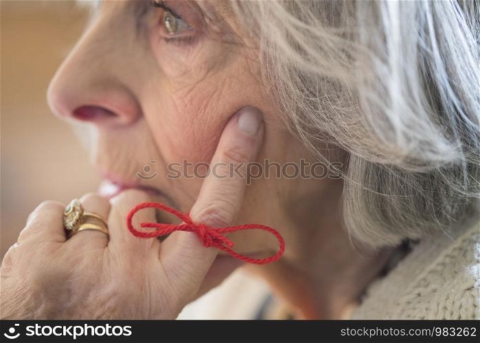 Close Up Of Senior Woman With String Tied Around Finger As Reminder