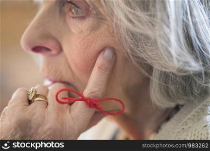 Close Up Of Senior Woman With String Tied Around Finger As Reminder