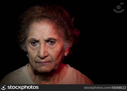 Close-up of serious woman over black background