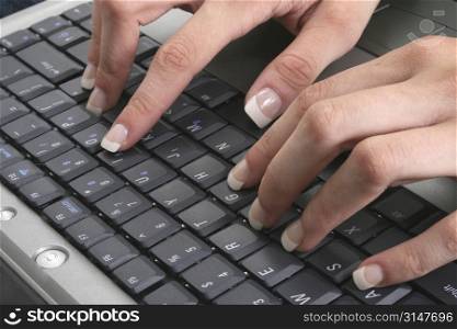 Close-up of sexy manicured hands on laptop keyboard.