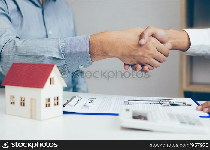 Close up of shaking hands with customer and real estate broker after signing a contract in home office.