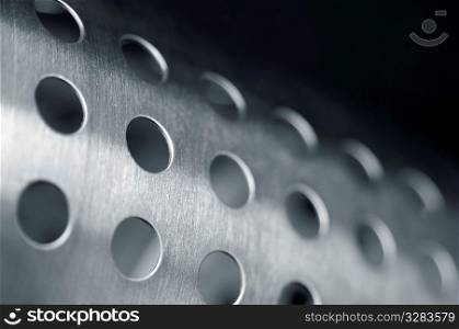 Close-up of shiney cylinder with holes.