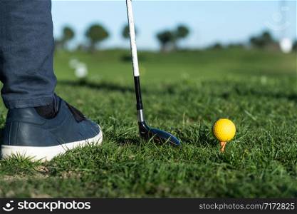 close-up of shoes, golf club, and golf ball on a driving range