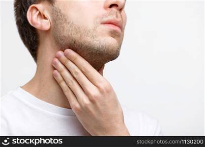 Close up of sick man suffering from throat problems, grey background, isolated. Lymph glands, painful swallowing, pharyngitis, laryngeal swelling concept. Inflammation of the upper respiratory tract