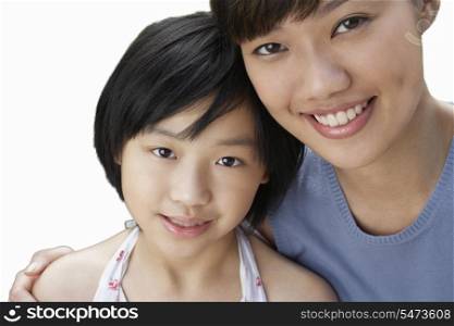 Close-up of sisters smiling over white background