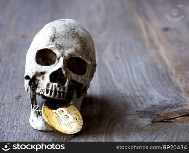 Close up of Skull biting Golden bitcoin on wooden table. The concept of investment and Fluctuation of bitcoin and cryptocurrency. The feeling of disappointed investors.