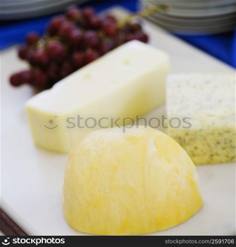 Close-up of slices of cheese with red grapes on a cutting board