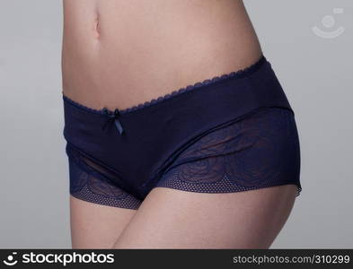 Close up of slim fit healthy girl in dark blue panties on white background