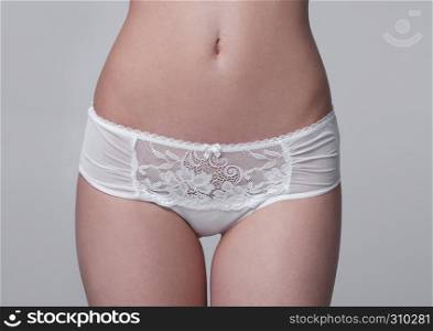 Close up of slim fit healthy girl in white panties on white background