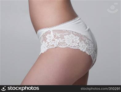 Close up of slim fit healthy girl in white panties on white background