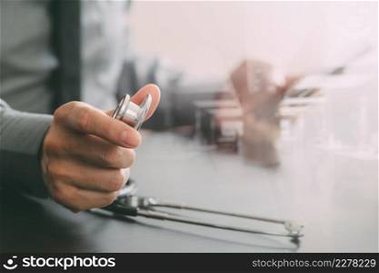 close up of smart medical doctor working with stethoscope and mobile phone on dark wooden desk in modern hospital