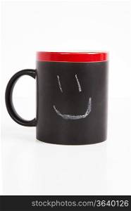Close-up of smiley drawn on cup over white background