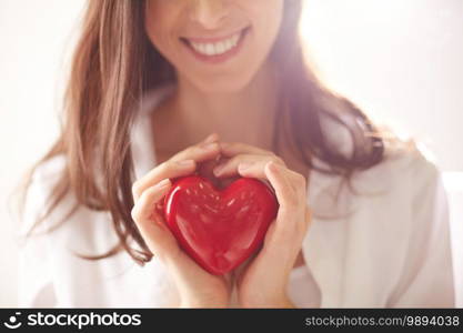 Close-up of smiling female holding red heart
